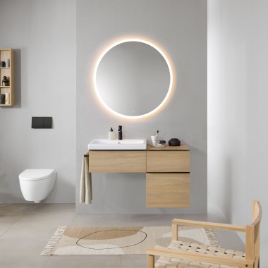 Kupaonica sa sivim zidovima, Geberitovim kupaonskim namještajem u drvu i okruglim ogledalom s rasvjetom Geberit Option