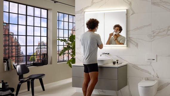 Muškarac se brije za umivaonikom s kupaonskim namještajem i elementom s ogledalom Geberit ONE
